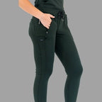 Close-up three-quarter view of women's scrub joggers 920 super stretch bottle green showing hand in pocket.