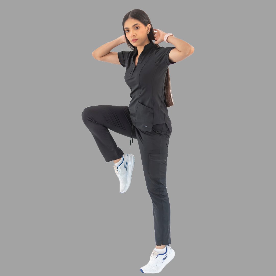 Women's black Style 930 scrub top, full body side view lifting one leg